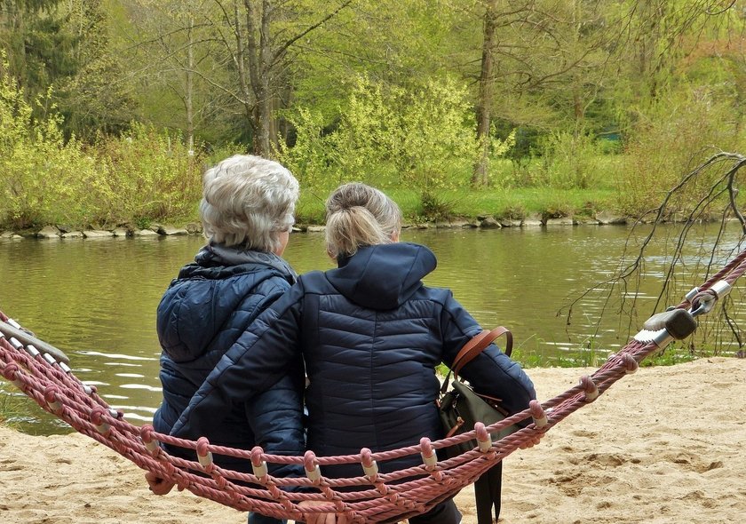 Zwei ältere Damen sitzen in einer Schaukel vor einem See